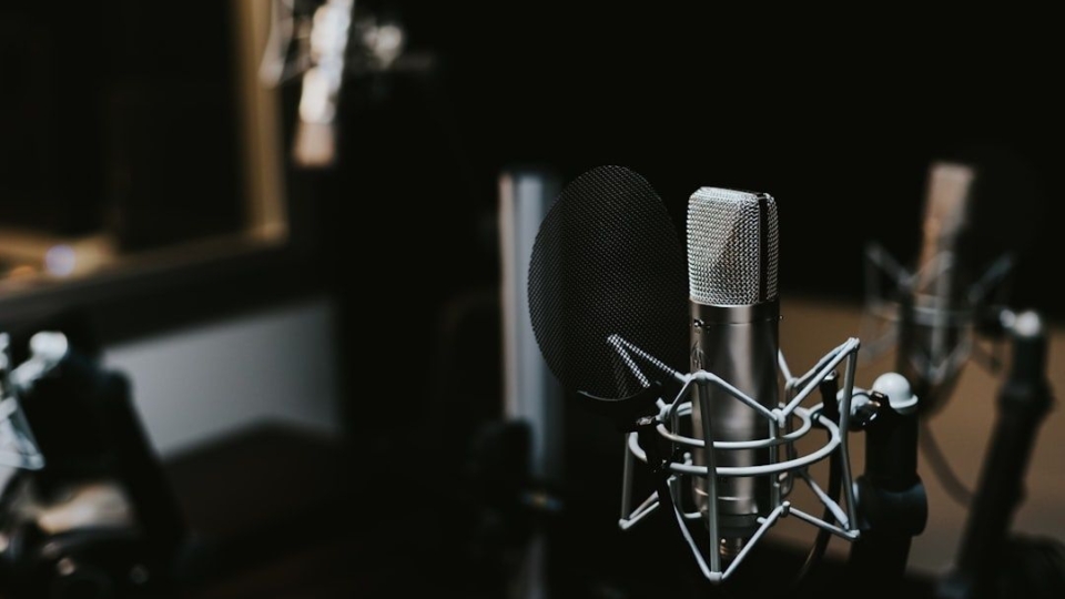 Studiomikrofon med popfilter i en mörk ljudinspelningsstudio
