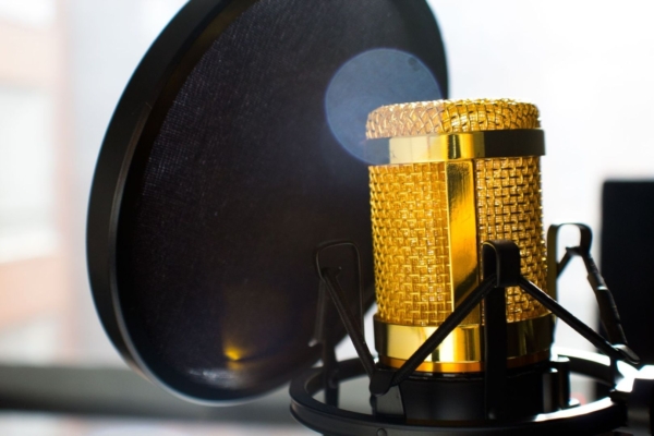 Guldig studiomikrofon bakom ett svart popfilter