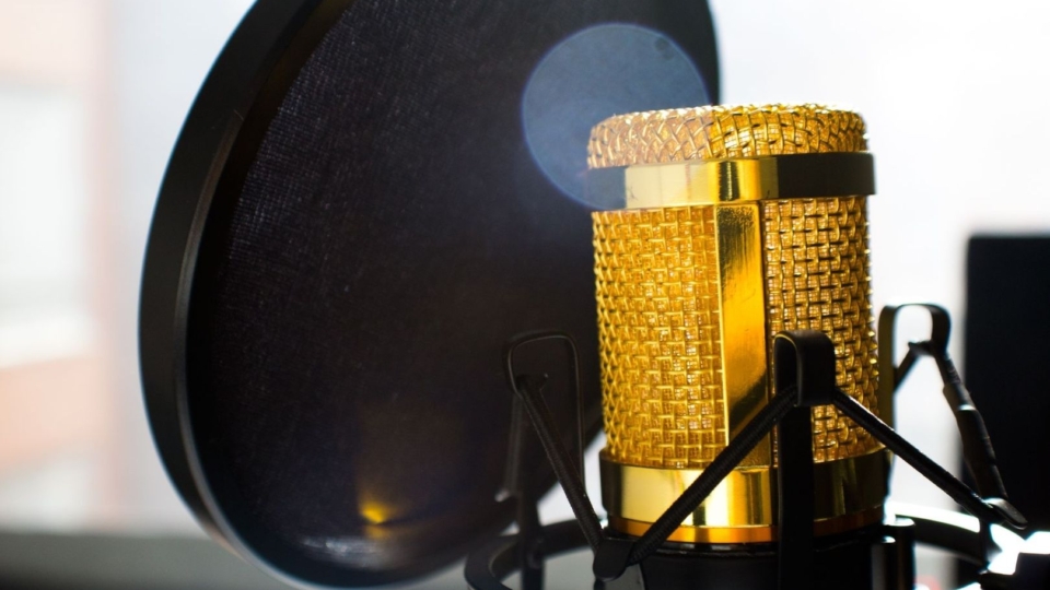 Guldig studiomikrofon bakom ett svart popfilter